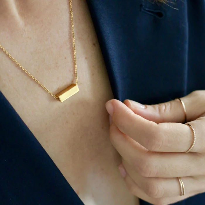 Femme portant un collier pendentif rectangulaire en or vermeil.