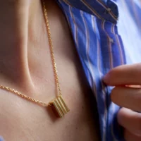 Femme portant un collier pendentif strié en or vermeil.