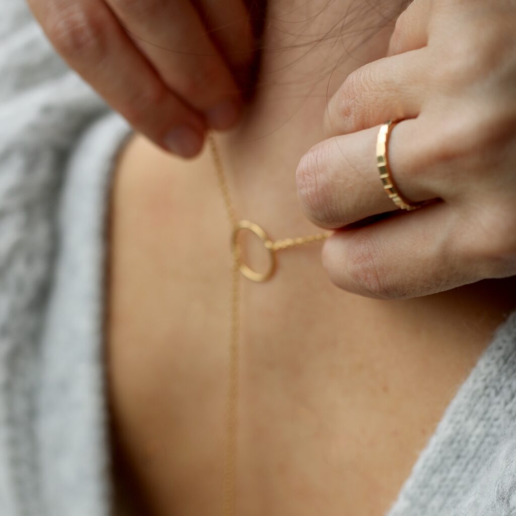 Les mains d'une femme brune tenant un long sautoir en or